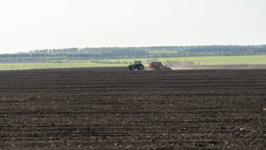 Bahar tarlası işi, traktör yeşil alanların arka planında buğday eker.