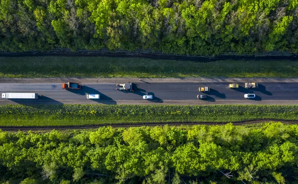 repair of the road, laying hot asphalt on the road going through the forest, the view from the quadcopter drone