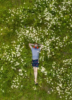 Solunum cihazında alerjisi ve gözlüğü olan biri papatya tarlasında uzanıyor ve temiz havanın tadını çıkarıyor.