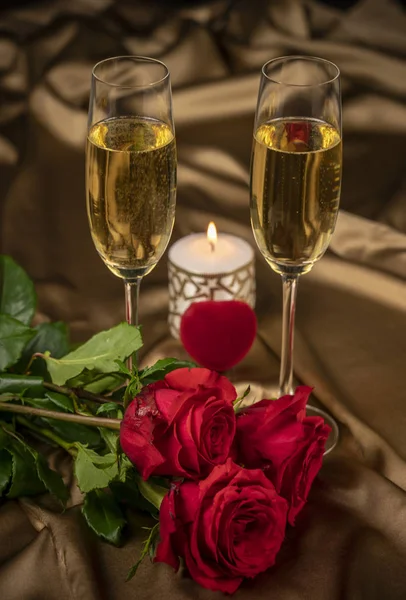 Tarjeta de San Valentín, dos copas de champán sobre un fondo dorado rosas rojas y un corazón rojo, una vela encendida —  Fotos de Stock
