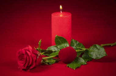 Kırmızı gül, kırmızı mum ve kırmızı kalp sevgililer günü, düğün günü, yıldönümü anısına kırmızı arka planda.