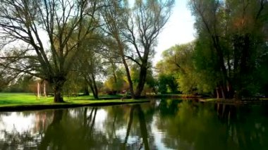 Sonbaharın başlarında güzel bir parkta renkli bir göl. Kamera suyun yüzeyinde uçuyor.