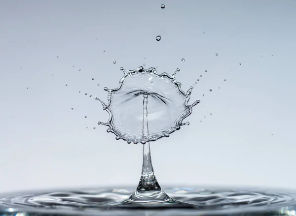 Gotas de água caem de uma altura de água pura e clara formando salpicos na forma de formas originais de guarda-chuvas, cogumelos e coroas — Fotografia de Stock