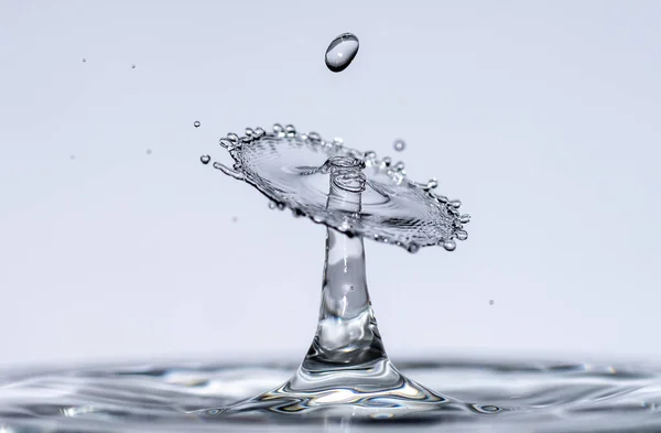 Gotas de água caem de uma altura de água pura e clara formando salpicos na forma de formas originais de guarda-chuvas, cogumelos e coroas — Fotografia de Stock