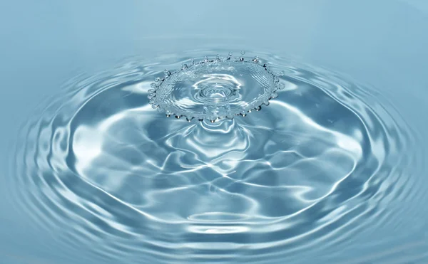 As gotas de água limpa e fresca caem de uma altura de água azul clara e transparente que forma salpicos na forma de números originais — Fotografia de Stock