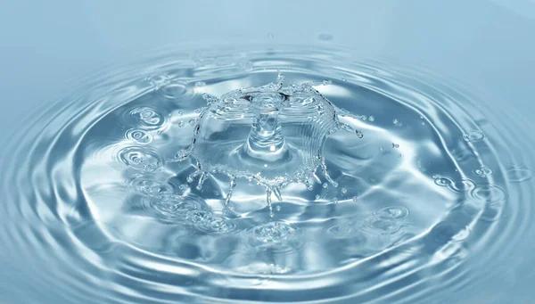 Капли чистой и пресной воды падают с высоты прозрачной голубой воды, образующей брызги в виде оригинальных фигур — стоковое фото
