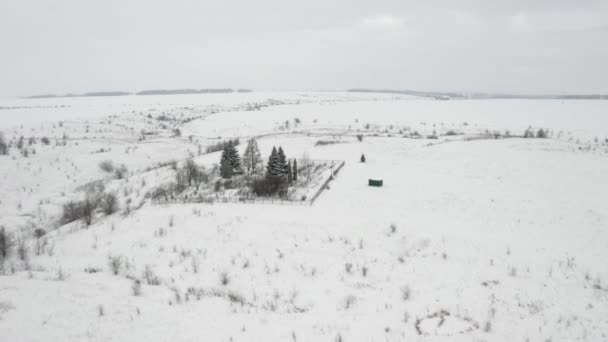 Vídeo aéreo, sobrevolando un cementerio rural cubierto de nieve situado al borde de un barranco — Vídeos de Stock