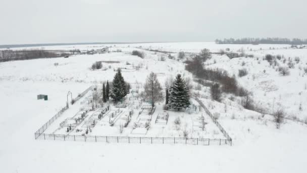 Vídeo aéreo, voando sobre um cemitério rural varrido pela neve localizado à beira de uma ravina — Vídeo de Stock