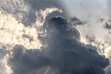 Solar beam is like a spotlight shining from behind the huge Cumulus clouds