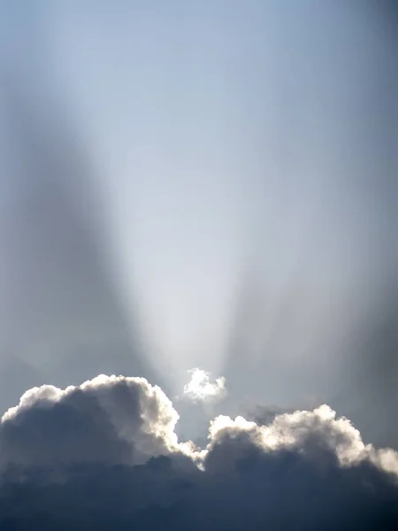 Sonnenstrahl ist wie ein Scheinwerfer, der hinter den riesigen Cumuluswolken hervorleuchtet — Stockfoto