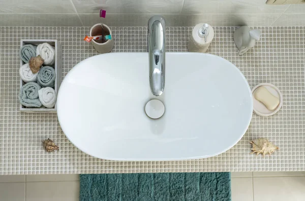 sink wash basin and personal hygiene items such as toothbrushes, soap, towel in the bathroom.