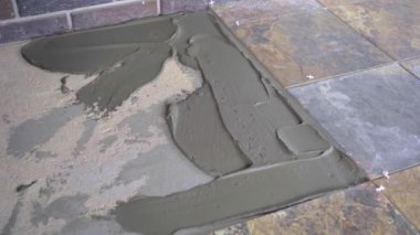Seramik fayansları yere seriyor, beton zemine tutkal sürüyor.