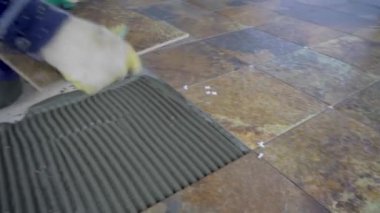 Seramik fayansları yere seriyor, usta fayansı tarakla yapıştırılan tutkala koyuyor.