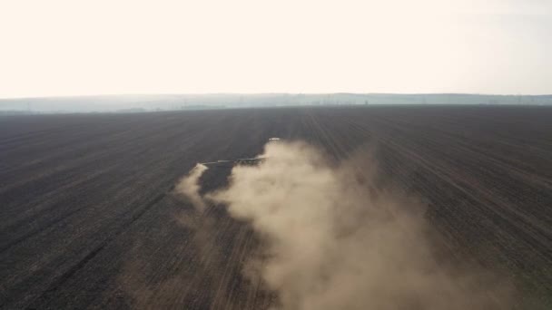 Trabajos de campo de primavera, un tractor con una sembradora montada siembra semillas en el suelo en un campo agrícola — Vídeo de stock