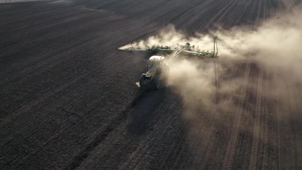 Lente veldwerk, een trekker met een gemonteerde zaaimachine zaaigoed in de grond op een landbouwveld — Stockvideo