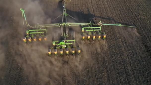 Trabajos de campo de primavera, un tractor con una sembradora montada siembra semillas en el suelo en un campo agrícola — Vídeo de stock