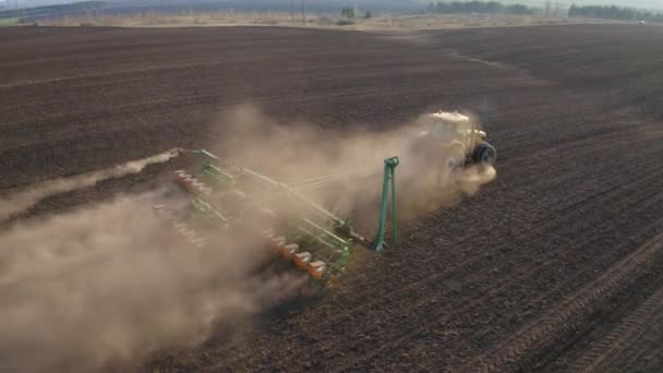 Travaux de printemps sur le terrain, un tracteur avec semoir monté sème des graines dans le sol sur un champ agricole 