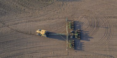 Spring field work, a tractor with a mounted seeder sow seeds in the ground on an agricultural field. aerial photos. clipart