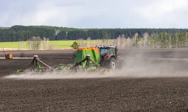 Trabajos de campo de primavera, un tractor con una sembradora arrastrada siembra semillas en un campo agrícola —  Fotos de Stock