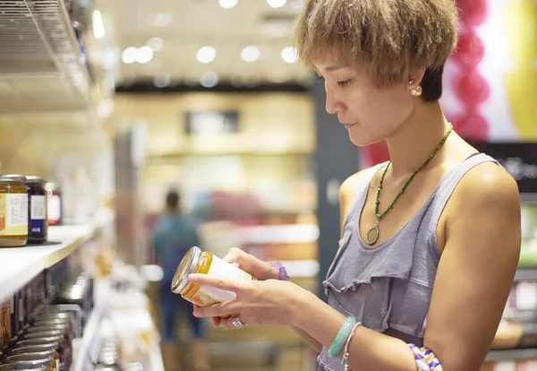 Mujer comprobar información sobre el paquete en el supermercado —  Fotos de Stock