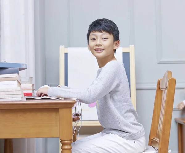 Asyalı çocuk evde kamera bakarak okuyor — Stok fotoğraf
