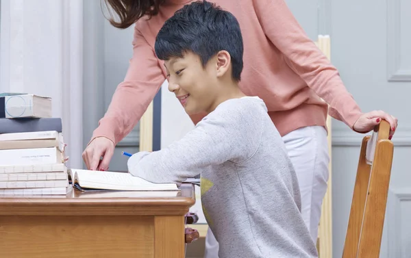 Genç Asyalı çocuk, annesi tarafından eğitilmiş. — Stok fotoğraf