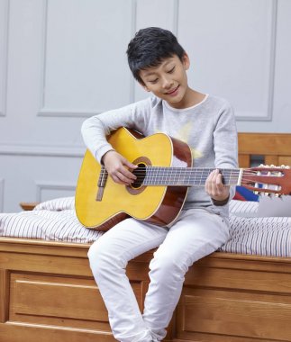 genç Asyalı çocuk evde gitar çalıyor