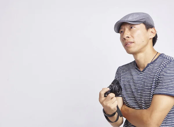 Azjatycka fotograf patrząc na odległość z kamerą w ręku na białym tle — Zdjęcie stockowe