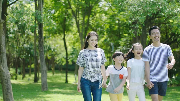 Chinese family smiling & walking together in park — Stock Photo, Image