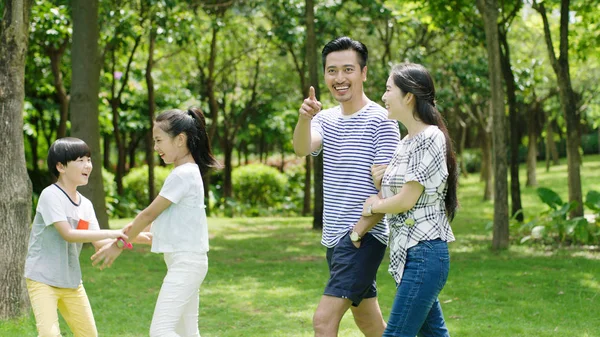 Asian family laughing & walking in park in summer