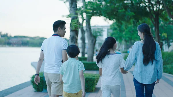 Vue arrière de la famille asiatique souriant et marchant sur la promenade en bord de mer au crépuscule — Photo