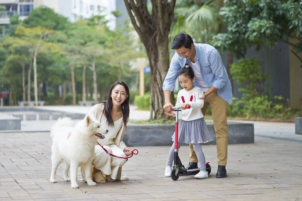 Asya veliler ve scooter köpek bahçede yürürken oynarken kızı