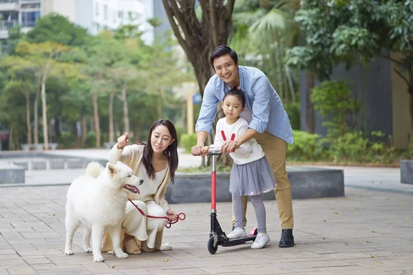 Asya veliler ve scooter köpek bahçede yürürken oynarken kızı