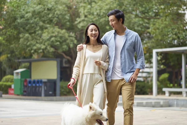 Asya çift bahçede yürürken köpek açık gülüyor