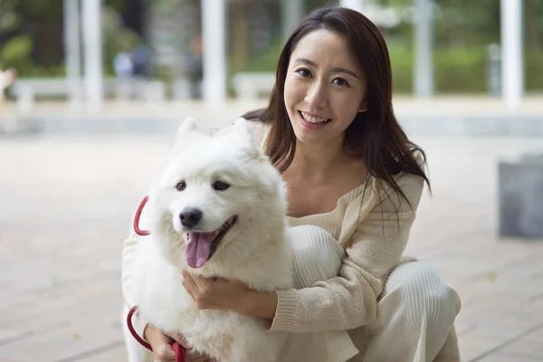 Asya Güzeli bahçede açık kamera gülümseyen köpeği kucaklayan
