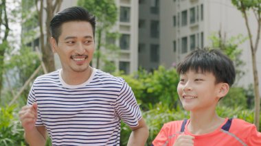 Çinli adam ve oğlu gülümseyen ve bahçede sabah koşu portresi