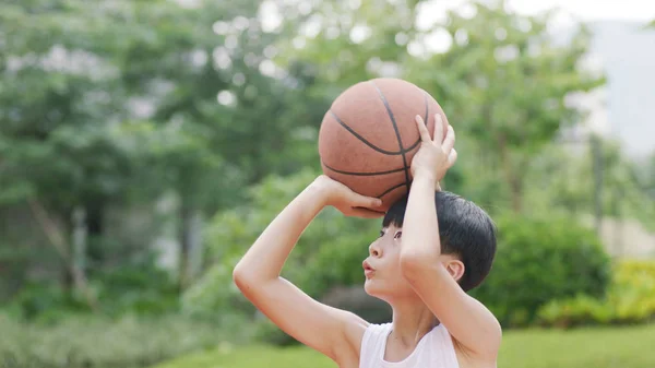 Genç Asyalı çocuk basketbol açık havada çekim için hazırlanıyor