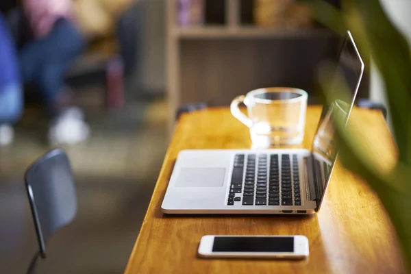 laptop, smart phone & glass of water on coffee shop table