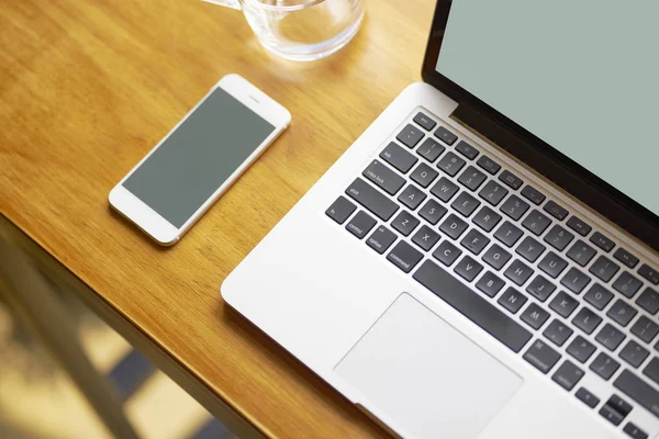 laptop, smart phone & glass of water on coffee shop table