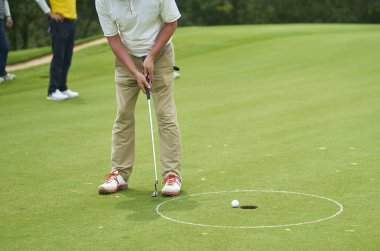 Tanınmayan Asya adam Golf topu yeşil yaz aylarında koyarak.