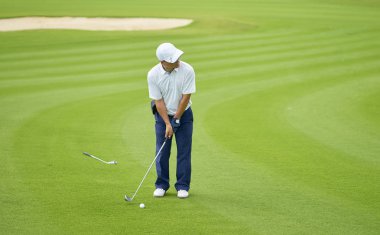 Asya golfçü hedefleyen ve koymak için hazırlama ders ayakta