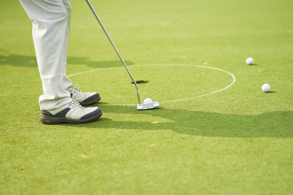 Tanınmayan Asya adam Golf topu yeşil yaz aylarında koyarak.