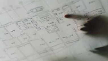 closeup silhouette of fingers pointg on blueprint when discussing