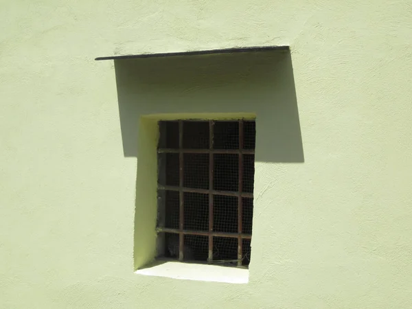 Fenêtre avec barreaux dans un mur jaune clair — Photo