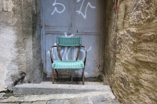 Patio chair covered with green plastic cord before a frontdoor — 스톡 사진