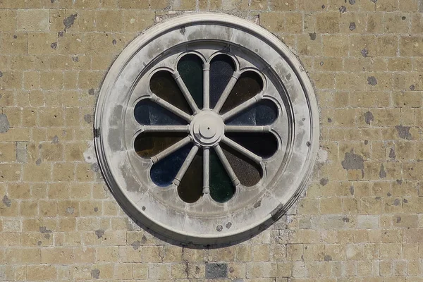 Ronde roos venster in een gele stenen muur — Stockfoto