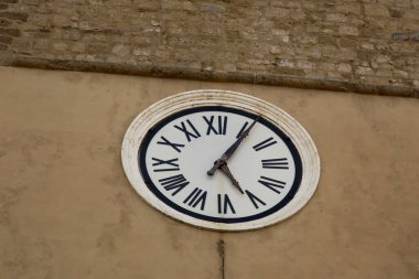 Pititgliano 'daki bir binanın duvarında Roma numaraları yazan bir saat.