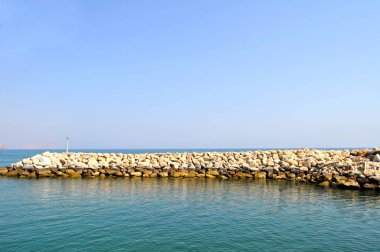 Mavi gökyüzüne karşı Umman Körfezi kıyısında dalgakıran