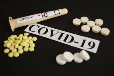 COVID-19 ilaçları - siyah arkaplanda test tüpleri ve tabletler