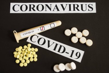 COVID-19 ilaçları - siyah arkaplanda test tüpü ve tabletler